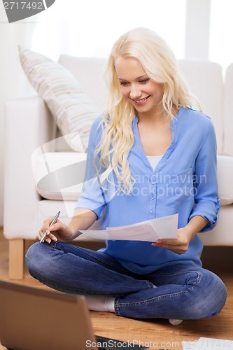 Image of smiling woman with papers, laptop and calculator