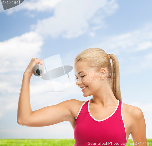 Image of young sporty woman with light dumbbell