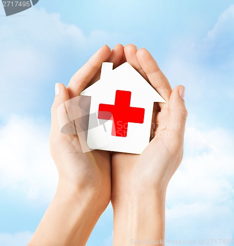 Image of hands holding paper house with red cross