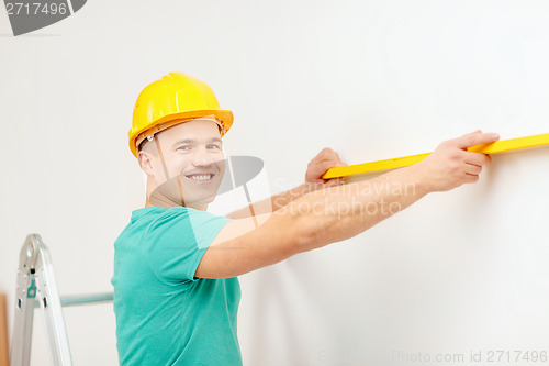 Image of smiling man building using spirit level to measure