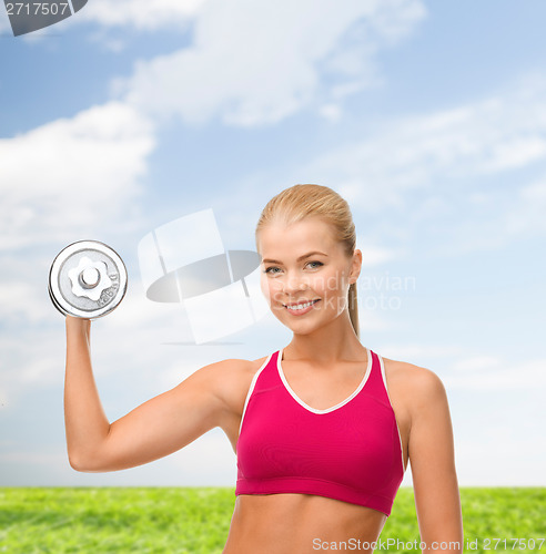 Image of smiling woman with heavy steel dumbbell