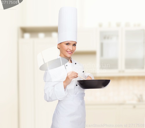 Image of smiling female chef with pan and spoon