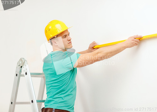 Image of smiling man building using spirit level to measure