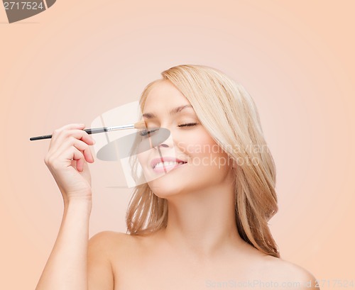 Image of beautiful woman with closed eyes and makeup brush