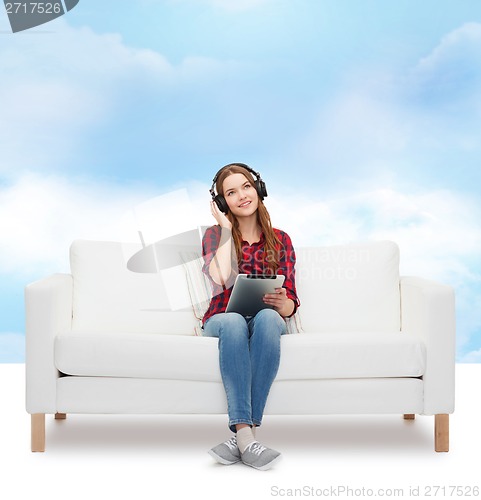 Image of girl sitting on sofa with headphones and tablet pc