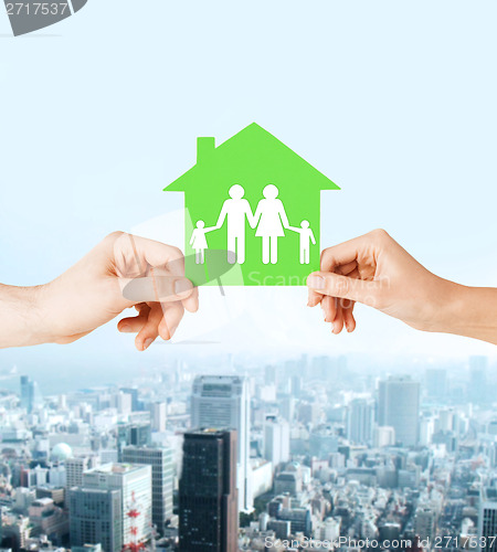 Image of hands holding green house with family