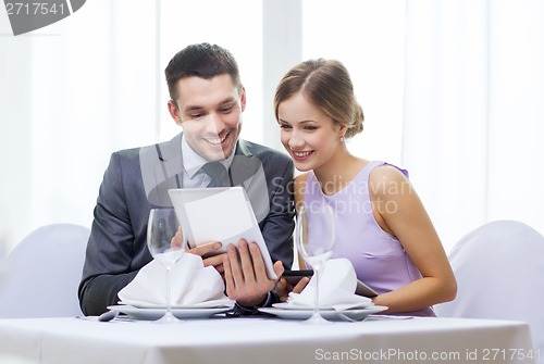 Image of couple with menus on tablet pc at restaurant