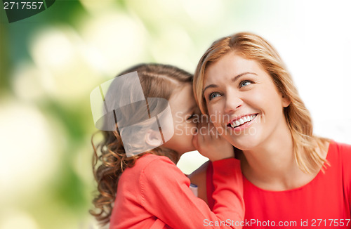 Image of smiling mother and daughter whispering gossip