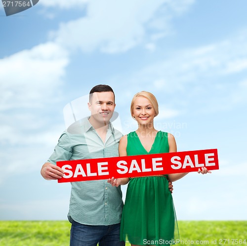 Image of smiling couple with sale sign