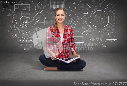 Image of smiling young woman sittin on floor with book