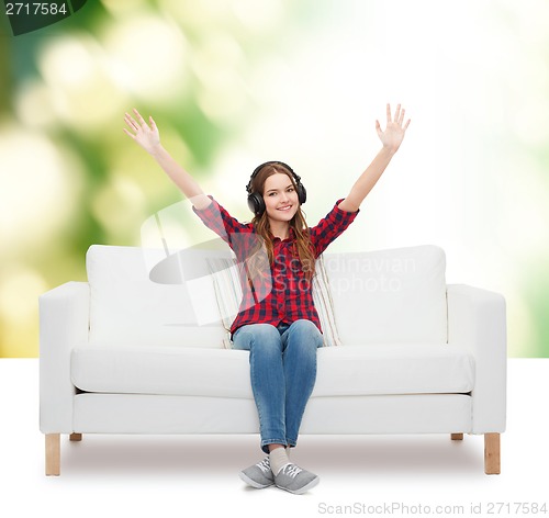 Image of teenage girl sitting on sofa with headphones