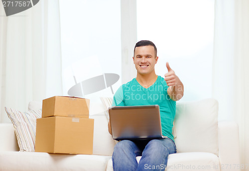 Image of man with laptop and cardboard boxes at home