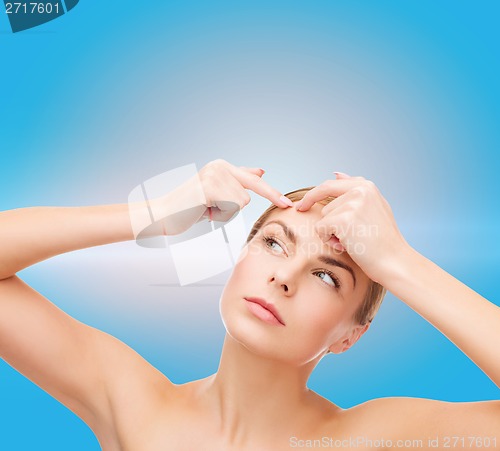 Image of young woman squeezing acne spots