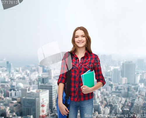 Image of smiling female student with bag and notebooks