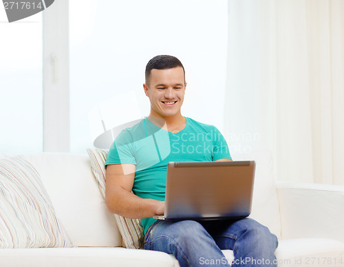Image of smiling man working with laptop at home
