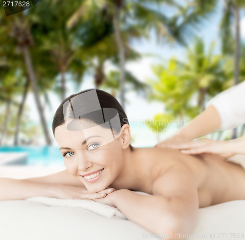 Image of smiling woman in spa salon getting massage