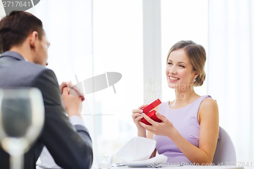 Image of excited young woman looking at boyfriend with box
