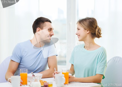 Image of smiling couple having breakfast at home