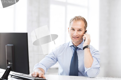 Image of smiling businessman with smartphone in office