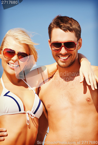 Image of happy couple in sunglasses on the beach