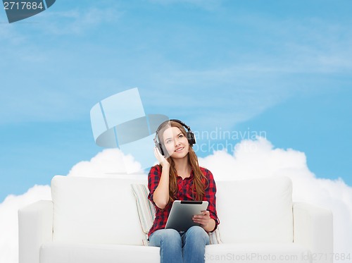 Image of girl sitting on sofa with headphones and tablet pc