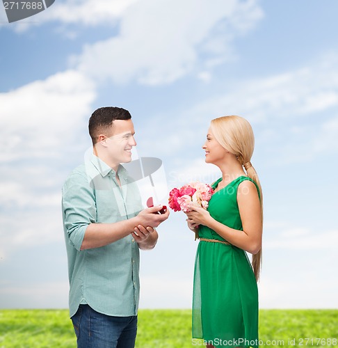 Image of smiling couple with flower bouquet and ring