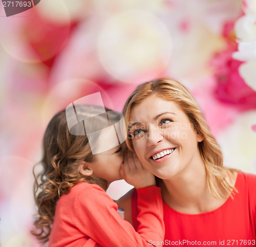 Image of smiling mother and daughter whispering gossip