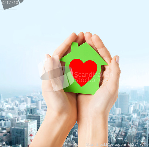 Image of hands holding green paper house