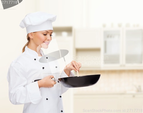 Image of smiling female chef with pan and spoon