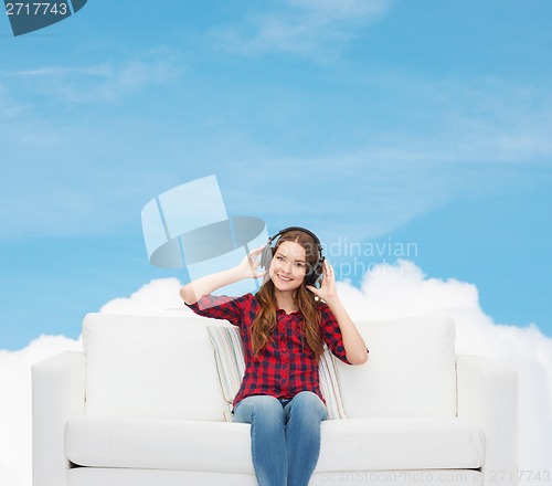 Image of teenage girl sitting on sofa with headphones