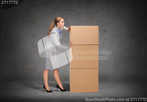 Image of busy businesswoman pushing tower of cardboards