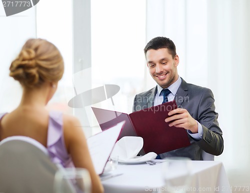 Image of smiling young man looking at menu at restaurant