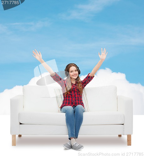 Image of teenage girl sitting on sofa with headphones