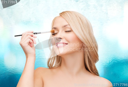 Image of beautiful woman with closed eyes and makeup brush