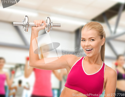 Image of smiling woman with heavy steel dumbbell