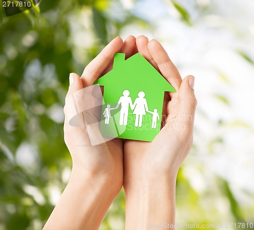 Image of hands holding green house with family