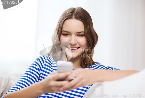 Image of smiling teenage girl with smartphone at home