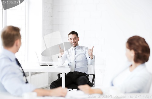 Image of businessman showing thumbs up in office