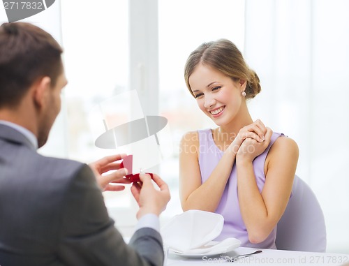 Image of excited young woman looking at boyfriend with ring