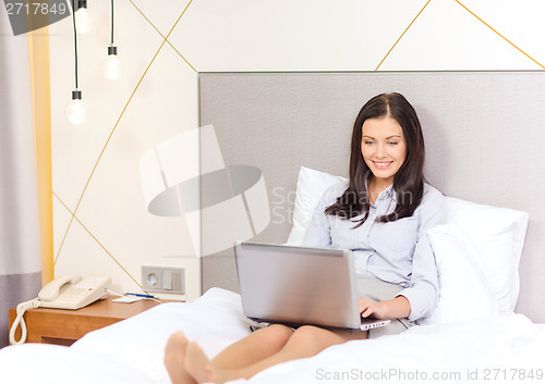 Image of happy businesswoman with laptop in hotel room