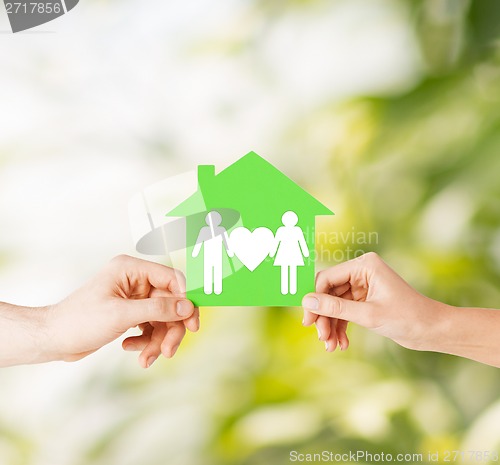 Image of hands holding green house with family