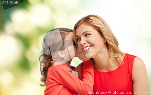 Image of smiling mother and daughter whispering gossip