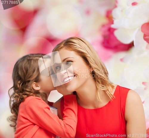 Image of smiling mother and daughter whispering gossip