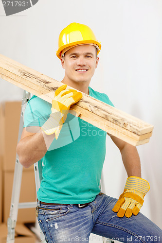 Image of smiling manual worker in helmet with wooden boards