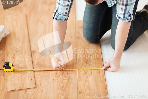 Image of close up of male hands measuring wood flooring