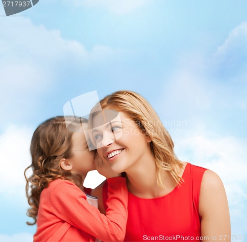 Image of smiling mother and daughter whispering gossip