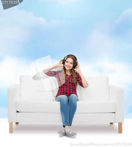 Image of teenage girl sitting on sofa with headphones