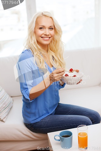 Image of smiling woman with bowl of muesli having breakfast