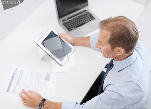 Image of businessman with tablet pc and papers in office