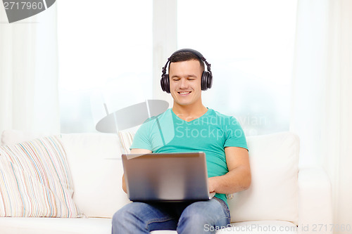 Image of smiling man with laptop and headphones at home